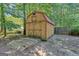 Wooden shed in the backyard with a red roof and double doors, surrounded by trees and a wooden fence at 127 Muirwood Dr, Temple, GA 30179
