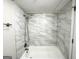 Bathroom tub and shower with white marbled tile and chrome shower head at 3995 Willowbrook Dr, Douglasville, GA 30135