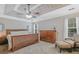 A primary bedroom showcases a tray ceiling, ceiling fan, neutral walls, natural light, and wood furniture at 2060 Lake St, Loganville, GA 30052