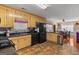 Open-concept kitchen with black appliances, natural-finish cabinets, and tile flooring at 425 Wendy Ct, Mcdonough, GA 30252