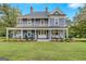 Charming two-story blue home featuring a large wrap-around porch and well-manicured lawn at 29 Indian Creek Rd, Locust Grove, GA 30248