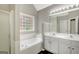 Bright bathroom features a double vanity, soaking tub, and glass block window for natural light at 35 Wenham Ln, Sharpsburg, GA 30277