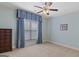 Cozy bedroom featuring a ceiling fan, neutral carpet, and window with blue curtains at 1442 Swiftwater Cir, Mcdonough, GA 30252