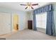 Bedroom featuring neutral carpet, ceiling fan, and window with decorative blue curtains at 1442 Swiftwater Cir, Mcdonough, GA 30252