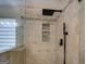 Shower features tan tiling with a decorative tile strip, black shower head and built-in shelving at 1484 Stephens Pond Vw, Loganville, GA 30052
