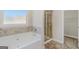 Bright bathroom featuring a soaking tub, tiled shower, and large window for natural light at 1141 Abundance Dr, Locust Grove, GA 30248