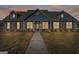 Charming single-story home featuring a brick facade, dormer windows, and well-maintained landscaping at dusk at 1141 Abundance Dr, Locust Grove, GA 30248