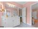 Pink bathroom featuring a white vanity, large mirror, and tile flooring, leading into an adjacent room at 127 Darwish Dr, Mcdonough, GA 30252