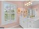 Bright bathroom with a white vanity, decorative mirror, and natural light from a large window with shutters at 127 Darwish Dr, Mcdonough, GA 30252
