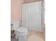 A view of the toilet and shower behind a white shower curtain in a bathroom with tile flooring at 127 Darwish Dr, Mcdonough, GA 30252