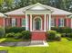 Inviting front porch with brick steps, white columns, and manicured shrubbery for a classic look at 127 Darwish Dr, Mcdonough, GA 30252