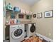 Functional laundry room with front load washer and dryer, storage shelf, and black and white tile floor at 127 Darwish Dr, Mcdonough, GA 30252