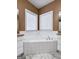 Bathroom with a corner tub and white tile, flanked by white cabinets and granite countertops at 340 Antebellum Way, Fayetteville, GA 30215