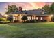Expansive backyard of brick home features a covered patio, mature trees, and lush green lawn at sunset at 248 Montrose Dr, Mcdonough, GA 30253