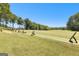 Open driving range with tee stations and distant green, framed by trees at 248 Montrose Dr, Mcdonough, GA 30253
