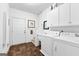 Bright laundry room featuring tiled floor, utility sink, washer, dryer, and white storage cabinets at 248 Montrose Dr, Mcdonough, GA 30253