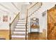 Grand foyer features hardwood floors, staircase with iron railings, and decorative wood barn door at 2770 Stonehill Way, Cumming, GA 30041
