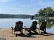 Lake view featuring waterfront, chairs, boat house, and trees under a sunny, clear sky at 306 N Meade Dr, Peachtree City, GA 30269