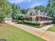 Charming brick home with a long, covered porch, a large driveway and detached garage surrounded by mature trees at 1302 Eddie Craig Ct, Mcdonough, GA 30252