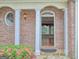 Covered doorway with brick wall and white pillars leading into entry with hard wood floors at 187 Eagles Club Dr, Stockbridge, GA 30281