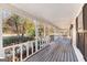 Long, covered porch with wooden flooring, white railings and views of the wooded property at 75 Antioch Rd, Mcdonough, GA 30252