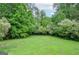 Lush backyard featuring a well-maintained lawn and mature trees, offering a serene outdoor space at 830 Montego Sw Way, Lilburn, GA 30047