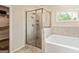 Bathroom with glass enclosed shower with ceramic tile backsplash, tub, and window at 107 Corinth Reserve Pl, Grantville, GA 30220