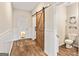 Hallway with wood-look flooring, sliding barn door, and access to the half bathroom at 107 Corinth Reserve Pl, Grantville, GA 30220