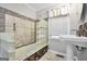 Bright bathroom features a window, shower-tub with glass block, tile surround, and classic pedestal sink at 701 Mask Rd, Brooks, GA 30205