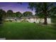 Charming white brick home with a lush green lawn and mature trees at dusk at 701 Mask Rd, Brooks, GA 30205