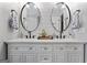 Bright bathroom featuring double vanity, modern fixtures, white cabinets, and eye-catching round mirrors at 4186 Highway 138 Sw, Stockbridge, GA 30281