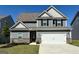 Charming two-story home with a gray exterior, black shutters, manicured lawn and a two car garage at 438 Prescott Way, Villa Rica, GA 30180