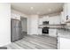 Well-lit kitchen features stainless steel appliances, white cabinetry, granite countertops, and wood-look flooring at 448 Prescott Way, Villa Rica, GA 30180