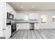 Modern kitchen with stainless steel appliances, white cabinets, and gray wood look floors at 448 Prescott Way, Villa Rica, GA 30180