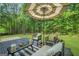 Back deck with seating under an umbrella; backyard with green grass and trees at 242 Greenland Dr, Mcdonough, GA 30253