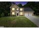 Two-story brick home with a two-car garage, large driveway, and lush green lawn at dusk at 242 Greenland Dr, Mcdonough, GA 30253