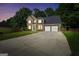 Two-story brick home with a two-car garage, large driveway, and lush green lawn at dusk at 242 Greenland Dr, Mcdonough, GA 30253