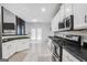 Bright kitchen with white cabinets, black countertops, stainless steel appliances, and tiled floors at 242 Greenland Dr, Mcdonough, GA 30253