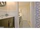 Bathroom featuring wainscoting, a dark vanity, and stylish mirror with a view of the hallway at 200 Doe Run, Peachtree City, GA 30269