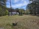 View of home with metal roof and gravel driveway, nestled among lush greenery and trees at 4064 Post Rd, Winston, GA 30187