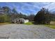 Single story home with metal roof, light siding, wooden porch, gravel driveway, and surrounding greenery at 4064 Post Rd, Winston, GA 30187