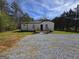 Attractive home with a metal roof, light siding, wooden porch, and a gravel driveway on a sunny day at 4064 Post Rd, Winston, GA 30187