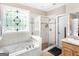 Bright bathroom featuring a shower, bathtub, and a window with decorative stained glass at 1103 Wilder Ct, Mcdonough, GA 30252