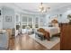 Light-filled bedroom with hardwood floors, tray ceilings, a ceiling fan, and a large picture window at 1103 Wilder Ct, Mcdonough, GA 30252