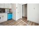 Bright kitchenette featuring sleek laminate flooring, white cabinetry, a blue dishwasher, and a side door entry at 2047 Charter Ln, Lithonia, GA 30058