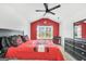 Bright bedroom with red accent wall, and a dark ceiling fan, desk, and dresser at 3709 Royer Ln # 23, Hampton, GA 30228