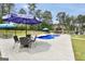 Backyard pool area featuring patio tables with umbrellas and outdoor kitchen, perfect for entertaining at 3709 Royer Ln # 23, Hampton, GA 30228