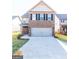 Two-story home featuring a brick facade, black shutters, a front yard, and a two-car garage at 2373 Aukerman Trce # 83, Hampton, GA 30228