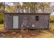 Gray outbuilding with a gray trim door, window, decorative exterior, and patio seating at 59 S Old Hwy 27, Roopville, GA 30170