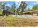 View of the backyard showcasing the in-ground pool, grassy area, and surrounding trees at 130 Ashley Trace Dr, Locust Grove, GA 30248